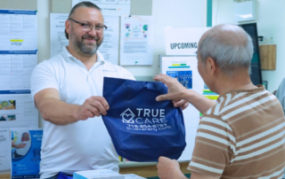True Care rep handing a branded bag to an older adult